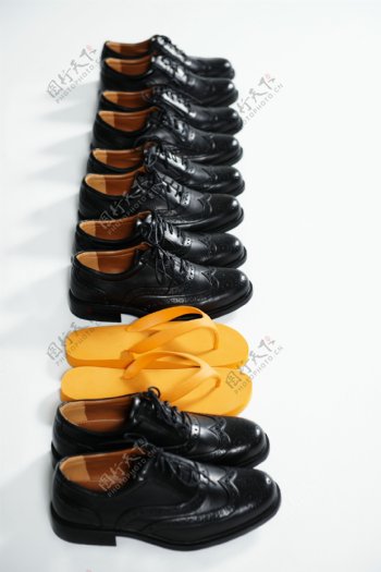 一排皮鞋中的黄色凉拖鞋图片