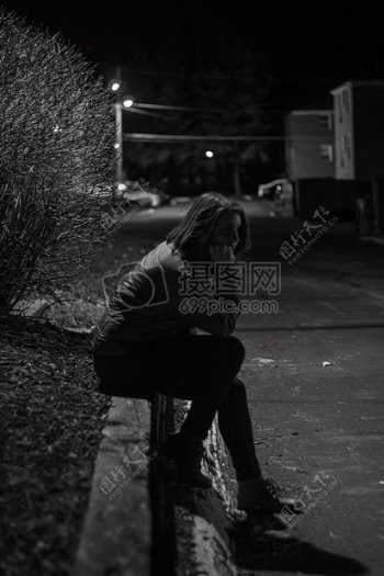 女人穿着夹克晚间期间坐在混凝土