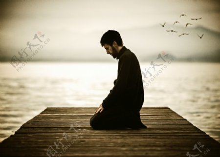 坐在岸边祈祷的男人图片