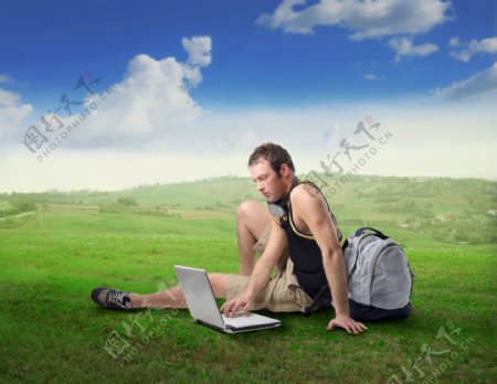 草原上玩电脑的时尚青年男性图片