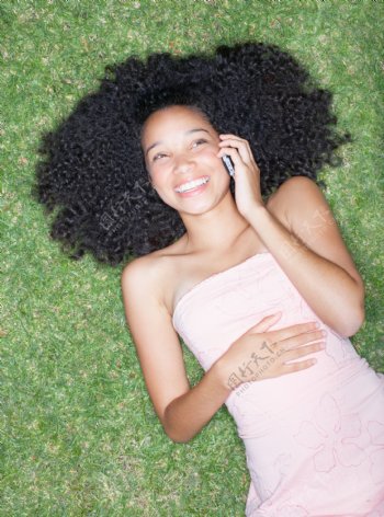 躺在草地上听电话的卷发女生图片