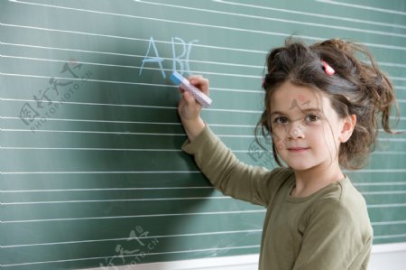 在黑板上写粉笔字的小女孩图片