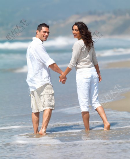 沙滩上牵手的年轻情侣图片