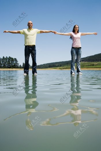 牵手一起站立在水面上的男女图片