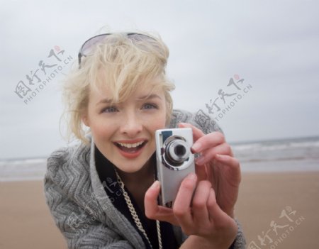 沙滩上正在拍照的女人图片