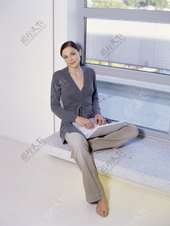 窗台上玩电脑的女人图片