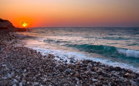 夕阳海浪海滩鹅卵石图片