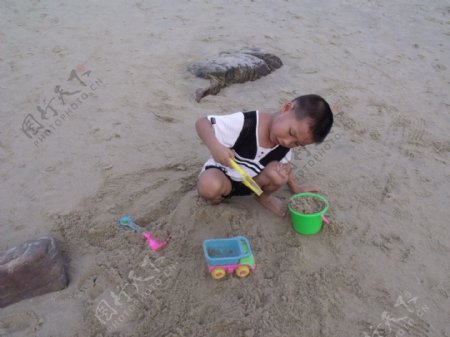 沙滩上玩沙子的小孩图片