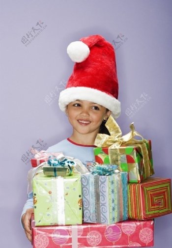 带圣诞帽手捧礼盒的微笑小女孩图片