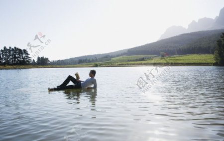 躺在水面上看书的男人图片