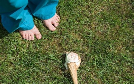 草地上孩子脚边的冰淇淋图片
