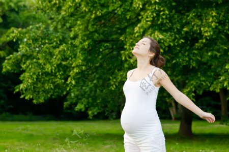 野外草地上呼吸新鲜空气的孕妇图片