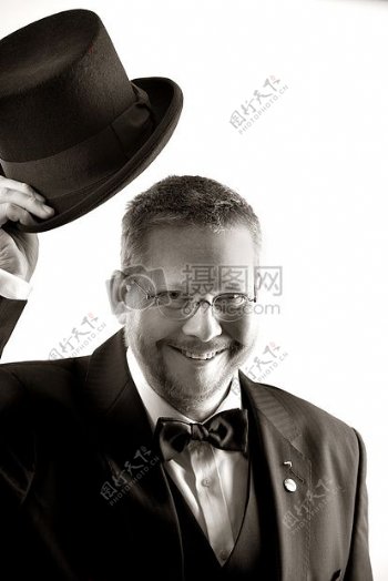 男子在Tuxedo和眼镜控股高帽灰度