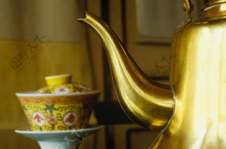 金色水壶旁一个茶杯图片