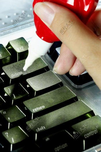 手拿清洁剂清洗键盘图片