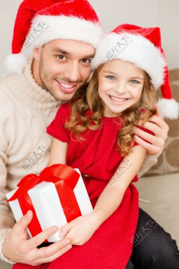 带着圣诞帽抱着礼物的男人与小女孩图片