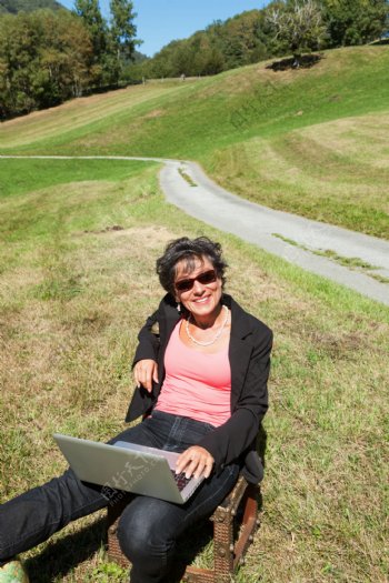 草地上玩电脑的女人图片