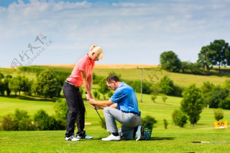 草地外国男人教外国女人打高尔夫球
