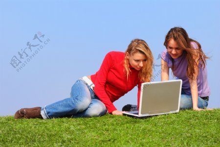 两个坐在草地上上网的女人图片