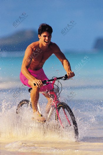 沙滩上骑自行车的男士图片
