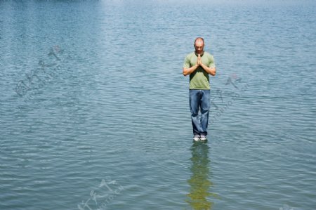 双手合十站立在水面上的男人图片