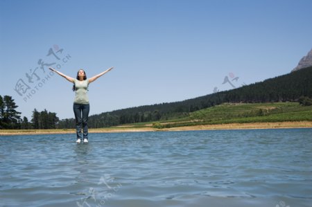 双手展开站立在水面的女人图片