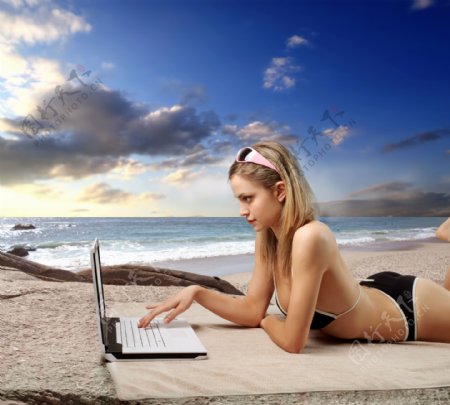 沙滩上玩电脑的美女图片