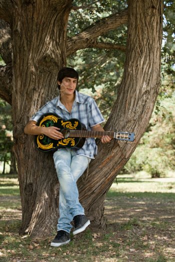 坐在树叉上弹吉它的男士图片