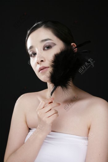 拿着黑色羽毛涂着烟熏妆的女人图片图片